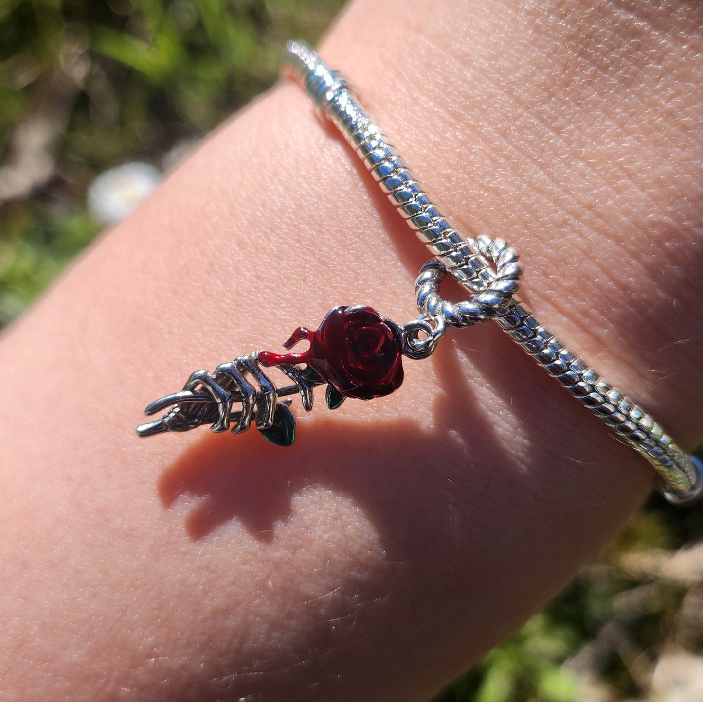 Apportez une touche de mystère et de beauté gothique à votre bracelet avec ce Charm Main Squelette Attrapant une Rose Rouge. Ce charm en argent 925 représente une main de squelette délicatement sculptée, tendue vers une rose rouge vibrante, symbole de passion et de beauté éternelle. La rose est magnifiquement détaillée avec des détails en émail rouge, contrastant avec la froideur du squelette. Une clé dorée pend à la rose, représentant l’accès à des secrets cachés ou à des émotions profondes.
Ce charm alli