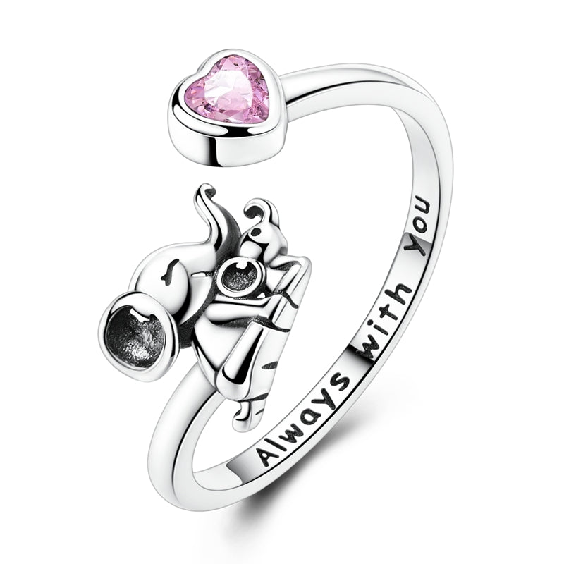 Cette bague ouverte en argent 925 met en scène un éléphant adulte serrant tendrement un éléphanteau, symbole d’amour protecteur, reliés à une extrémité ornée d’un cœur en cristal rose. L’inscription intérieure « Always with you » rappelle que ce lien est indéfectible, pour un bijou délicat qui évoque la présence rassurante d’un être cher au quotidien.