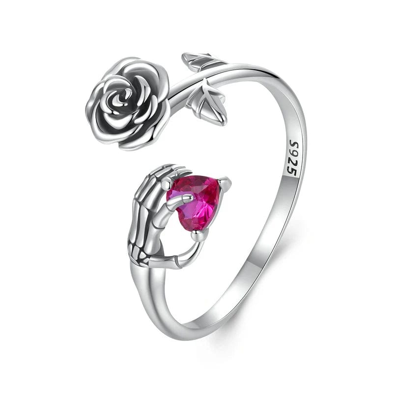 Cette bague ouverte en argent 925 met en scène une rose détaillée d’un côté et une main de squelette tenant un cristal cœur fuchsia de l’autre, pour un contraste poétique entre amour éternel et esthétique gothique. La forme ouverte permet d’ajuster légèrement la taille, ce qui en fait une bague réglable idéale pour s’adapter à plusieurs tours de doigt.