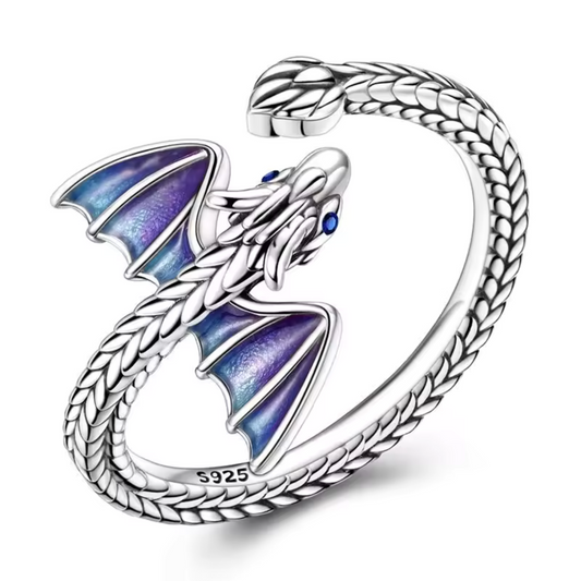 Affirmez votre style avec cette bague en argent 925 représentant un dragon majestueux. Son corps s’enroule autour du doigt tandis que ses ailes aux reflets violets et bleus apportent une touche de couleur intense et mystérieuse. Un bijou audacieux et élégant, parfait pour celles et ceux qui aiment les créations fantastiques.