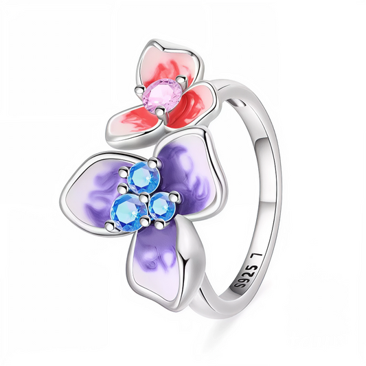 Apportez une touche de romantisme et de couleur à votre style avec cette bague en argent 925 ornée de deux fleurs délicates. Chaque fleur, l’une violette et l’autre rouge, est sublimée par un strass scintillant en son centre. Un bijou raffiné et féminin, parfait pour illuminer toutes vos tenues.