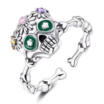 Affirmez votre style avec cette bague en argent 925 inspirée de l’univers festif du Día de los Muertos. Son design de tête de mort finement travaillé, décoré de motifs colorés et floraux, en fait un bijou original et plein de caractère. Parfait pour celles et ceux qui aiment les accessoires audacieux et symboliques.