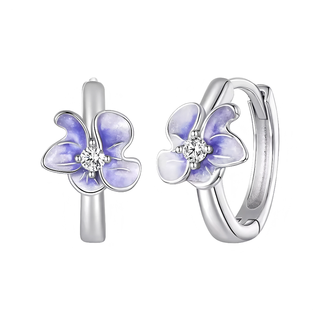 Ces boucles d’oreilles créoles fines arborent une petite fleur délicate en émail violet pastel, aux pétales légèrement ondulés et texturés pour un effet naturel et charmant. Au cœur de la fleur, un cristal rond étincelant ajoute une touche d’éclat précieux, illuminant subtilement le visage. Leur format huggie discret et féminin les rend idéales pour un style élégant et quotidien.