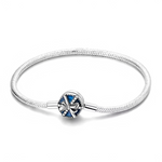 Ce bracelet en argent 925 présente un fermoir rond émaillé bleu, orné d’un nœud en relief bordé de petites billes métalliques, rappelant un coffret cadeau élégant.
Il est idéal pour marquer une occasion spéciale et peut accueillir des charms de type européen pour créer un bijou souvenir à offrir ou à s’offrir.