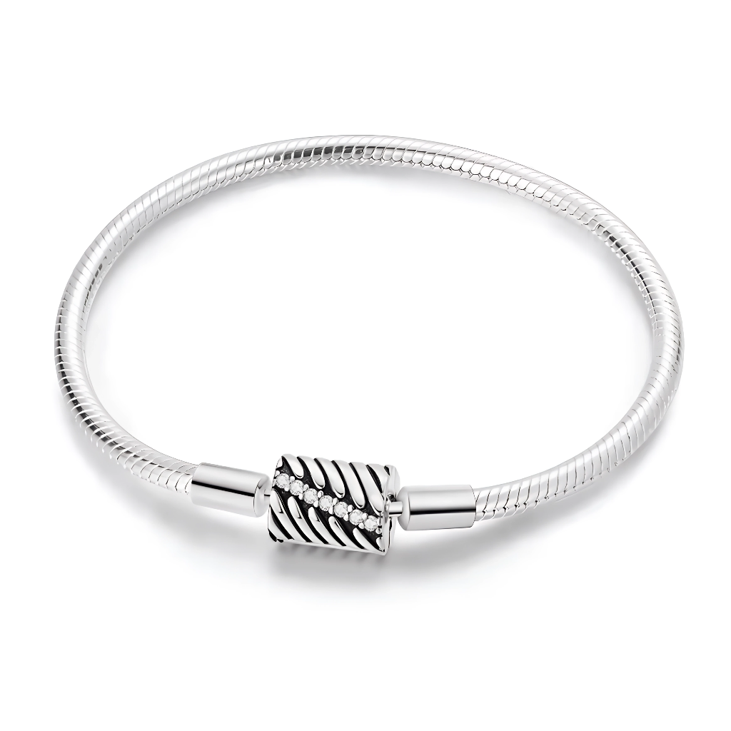 Ce bracelet en argent 925 se distingue par son fermoir barillet travaillé de stries obliques qui rappellent un motif de feuille, souligné par une rangée de zircones étincelantes.
Il offre une base élégante et moderne pour accueillir vos charms de type européen ou se porter seul pour un look minimaliste mais sophistiqué.
