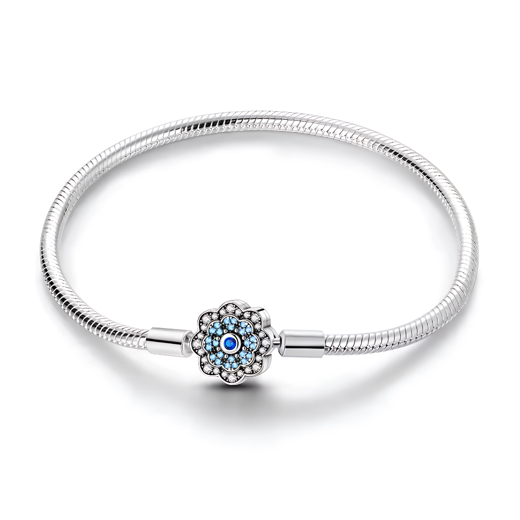 Ce bracelet en argent 925 est orné d’un fermoir en forme de fleur stylisée, dont le centre bleu rappelle l’œil porte-bonheur, symbole de protection et de chance.
Son design fin et lumineux se porte aussi bien au quotidien qu’en accumulation, et peut accueillir des charms de type européen pour créer un bijou personnalisé.