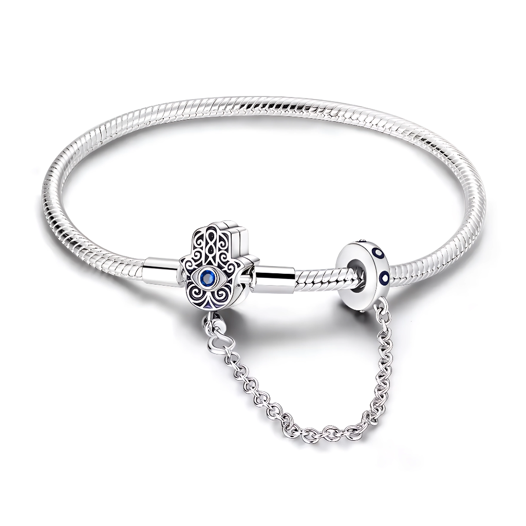Ce bracelet en argent 925 est doté d’un fermoir en forme de main de Fatma finement ajourée, rehaussée d’un cristal bleu central façon œil protecteur, symbole de chance et de protection.
La chaîne de sécurité intégrée, reliée à un anneau décoré de petits cristaux bleus, sécurise vos charms tout en ajoutant une touche élégante au poignet.