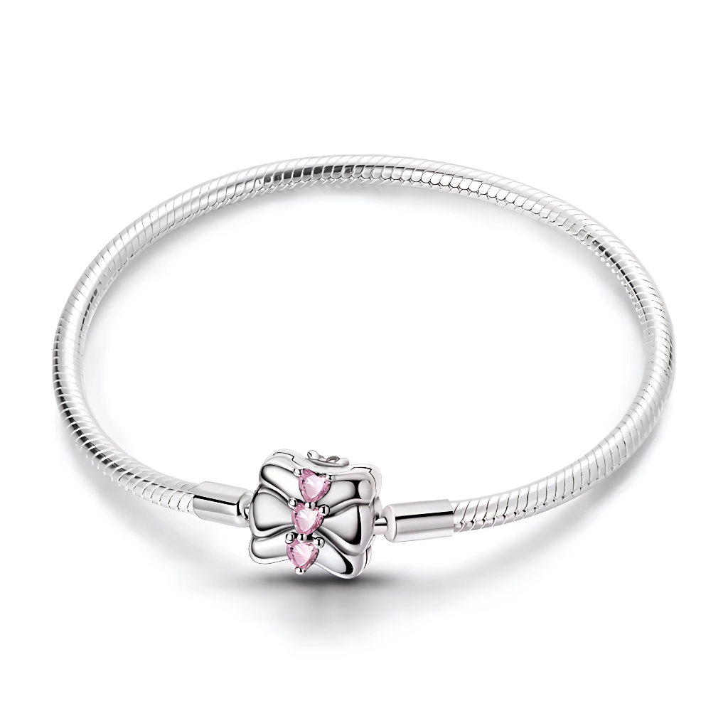 Ce bracelet en argent 925 présente un fermoir rectangulaire en forme de paquet cadeau, décoré d’un large nœud et de trois pierres en forme de cœur rose qui s’alignent au centre.
Il est parfait pour célébrer une occasion spéciale et peut accueillir des charms de type européen pour en faire un cadeau sentimental et personnalisable.