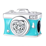 Ce charm vintage ludique reproduit un appareil photo rectangulaire turquoise brillant, lentille ronde ornée d'un cœur scintillant de cristaux transparents, poignée supérieure et viseur latéral détaillés. Deux cristaux blancs latéraux ajoutent éclat au boîtier argenté poli, avec suspension intégrée. Symbole de souvenirs précieux et créativité pétillante, il dynamise les bracelets d'un esprit aventurier joyeux.

Caractéristiques

Matière : Argent 925 avec émail turquoise et cristaux transparents blancs.
Desig