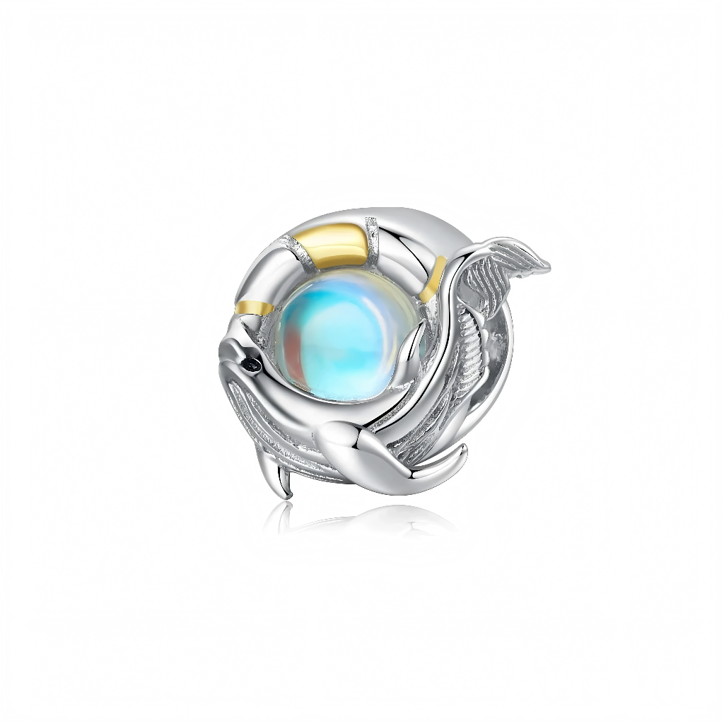 La pièce est en argent sterling 925, sculptée en forme de baleine qui tourne autour d’un cabochon rond irisé bleu‑blanc, rappelant une opale ou une bulle d’océan lumineuse. L’anneau qui entoure la pierre est partiellement plaqué d’un jaune doré, ce qui crée un contraste chaud avec les reflets froids du centre.
