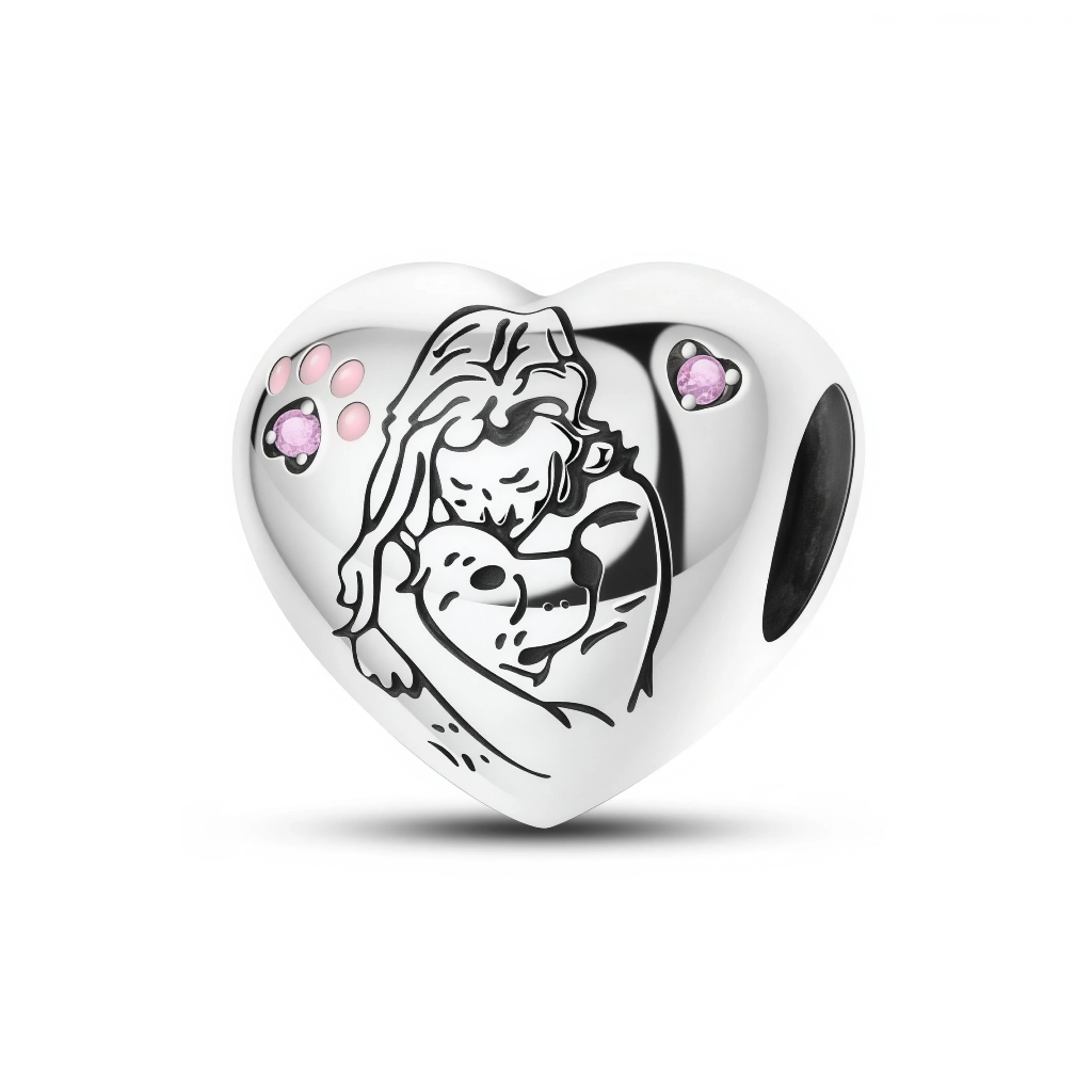 Ce charm en argent 925 a la forme d’un cœur bombé, gravé d’un dessin linéaire représentant une femme serrant tendrement son animal dans les bras, symbole du lien profond entre maître et compagnon. Deux petites empreintes en forme de cœur et de patte, serties de cristaux roses, ajoutent une touche douce et affectueuse au-dessus de la scène.