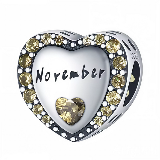 Illuminez le mois de novembre avec ce charm en argent 925 en forme de cœur, délicatement orné d’un contour de strass jaunes éclatants. Au centre, l’inscription « November » est gravée avec élégance, sublimée par une pierre jaune en forme de cœur qui symbolise la chaleur et la lumière en fin d’automne. Un bijou parfait pour célébrer un anniversaire de novembre ou offrir un cadeau lumineux et plein de sens.