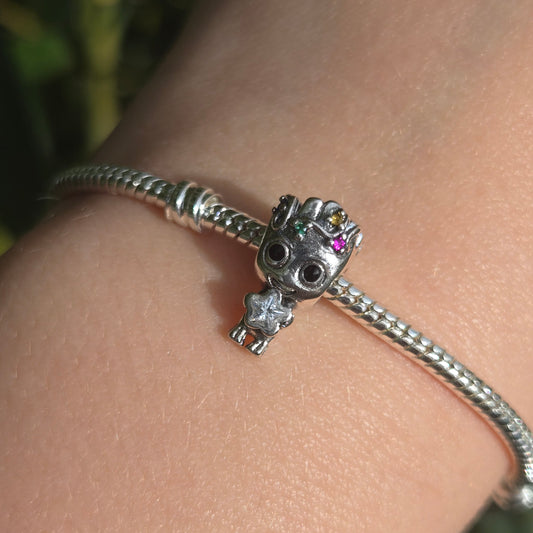 Ajoutez une touche festive et adorable à votre collection avec ce charm Groot en mode Noël. Fabriqué en métal argenté avec des accents de couleur en émail rouge et vert, ce charm représente Groot, le célèbre personnage des Gardiens de la Galaxie, enveloppé dans une guirlande de Noël scintillante, prêt à célébrer les fêtes. Les détails minutieux capturent son expression malicieuse et son côté espiègle, parfait pour les fans de Marvel et de la magie de Noël. Compatible avec les bracelets Pandora, ce charm uni