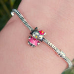 Apportez une touche adorable et emblématique à votre collection avec ce charm représentant Hello Kitty. Symbole de douceur et d'élégance, ce charm en argent 925 capture le célèbre visage de Hello Kitty avec son nœud distinctif. Parfait pour les fans de ce personnage intemporel, ce bijou ajoutera une touche mignonne et raffinée à votre bracelet ou collier.