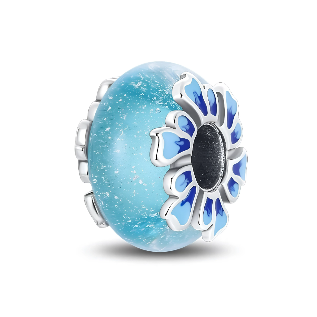 Ce charm en verre de Murano bleu mat évoque la surface de l’eau avec ses petites éclaboussures blanches, créant un effet givré et marin. De chaque côté, une grande fleur stylisée en argent 925 aux pétales émaillés de différents tons de bleu encadre l’ouverture et apporte du relief au bijou.

Caractéristiques :

-Matière : Verre de Murano bleu mat et argent 925 avec émail bleu.
-Design : Perle ronde effet mer givrée, ornée de fleurs émaillées de chaque côté.
-Coloris : Bleu lagon nuancé de blanc, argent bril