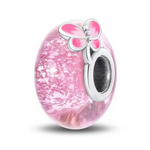 Ce charm met en lumière un verre de Murano rose tendre, traversé d’éclats translucides qui rappellent des pétales en suspension ou un ciel nuageux pastel. Un papillon rose en argent sterling&nbsp;925&nbsp;se pose délicatement sur le bord de la perle, symbolisant la douceur, le renouveau et la féminité.