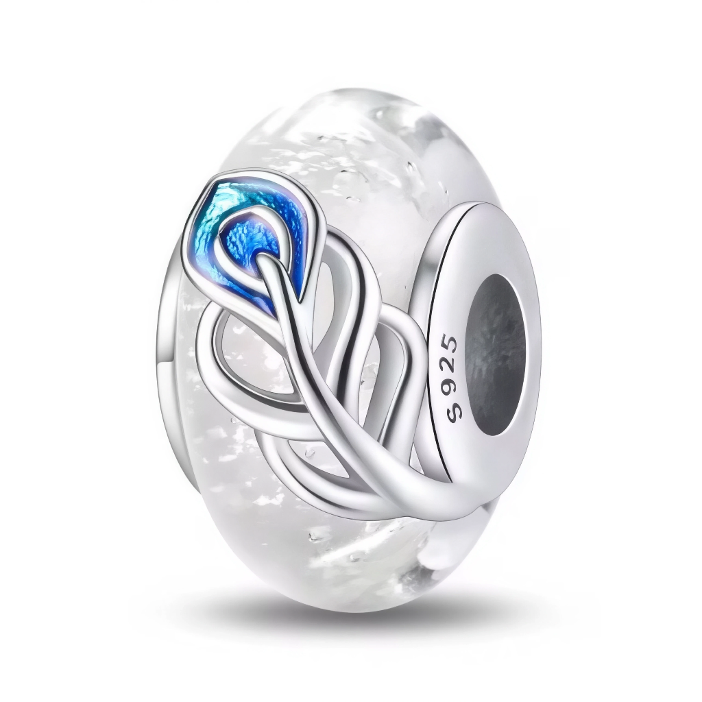 Ce charm en verre de Murano transparent présente de délicats effets givrés et bulles internes, qui captent la lumière comme de la glace ou des flocons en suspension. Une plume de paon stylisée en argent sterling&nbsp;925, soulignée d’émail bleu irisé, s’enroule autour de la perle pour apporter une touche élégante et exotique.