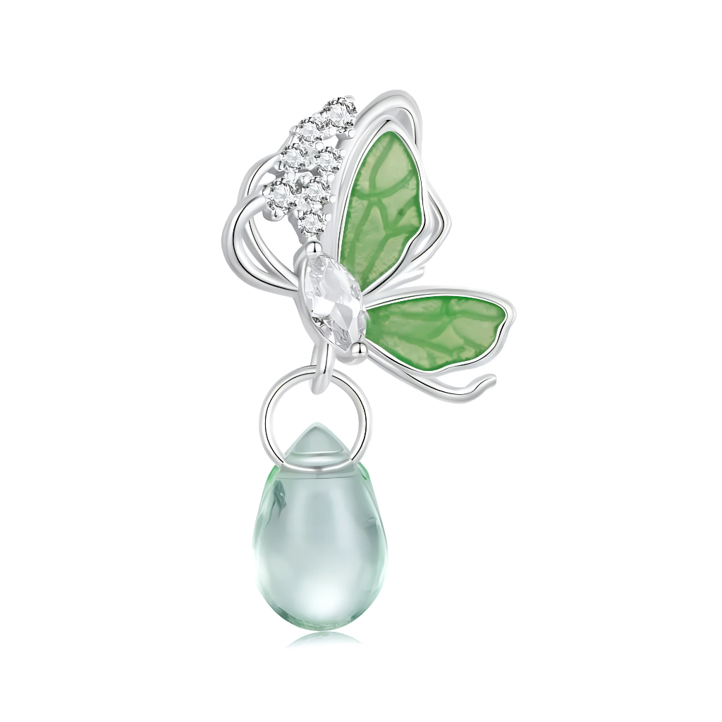 Ce charm pendant en&nbsp;argent&nbsp;925 représente un papillon délicat aux ailes vert émeraude translucides, fixé sur une structure argentée légère. Une goutte en verre vert pâle est suspendue sous le papillon, apportant un joli mouvement à chaque geste.