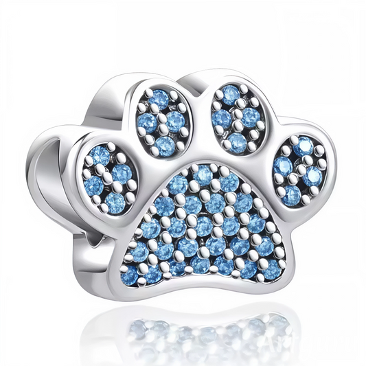 Affichez votre amour des animaux avec style grâce à ce charm patte de chien argentée orné de cristaux bleus éclatants ! Sa silhouette élégante et les pierres brillantes qui habillent chaque coussinet lui confèrent un éclat subtil et moderne. Parfait pour compléter un bracelet personnalisé ou offrir un clin d’œil tendre aux passionnés de chiens et de bijoux raffinés.