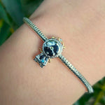 Ce charm rétro sophistiqué reproduit un pendule rond cadran blanc aux aiguilles stylisées, cadre ciselé motifs floraux, socle et jambes galbées avec cristaux bleu jaune étincelants. Les volutes dorées dynamiques et détails texturés évoquent élégance classique du pendentif. Symbole de moments précieux et tempo intemporel, il rythme les bracelets d'une mélodie vintage raffinée.

Caractéristiques

Matière : Argent 925 avec plaquage doré et cristaux bleu jaune.
Design : Pendule cadran aiguilles ciselures, jambe