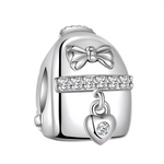 Le charm reprend les lignes d’un sac à dos lisse en argent, orné sur le haut d’un nœud délicat qui lui donne un look féminin et élégant. Une rangée de zircons scintillants traverse le centre comme une lanière brillante, d’où pend un petit cœur serti d’une pierre claire, rappelant les souvenirs précieux que l’on emporte partout avec soi. Ce bijou au design épuré s’associe aussi bien à un thème voyage qu’à un thème scolaire, et fait un cadeau symbolique pour une étudiante, une globe‑trotteuse ou toute personn