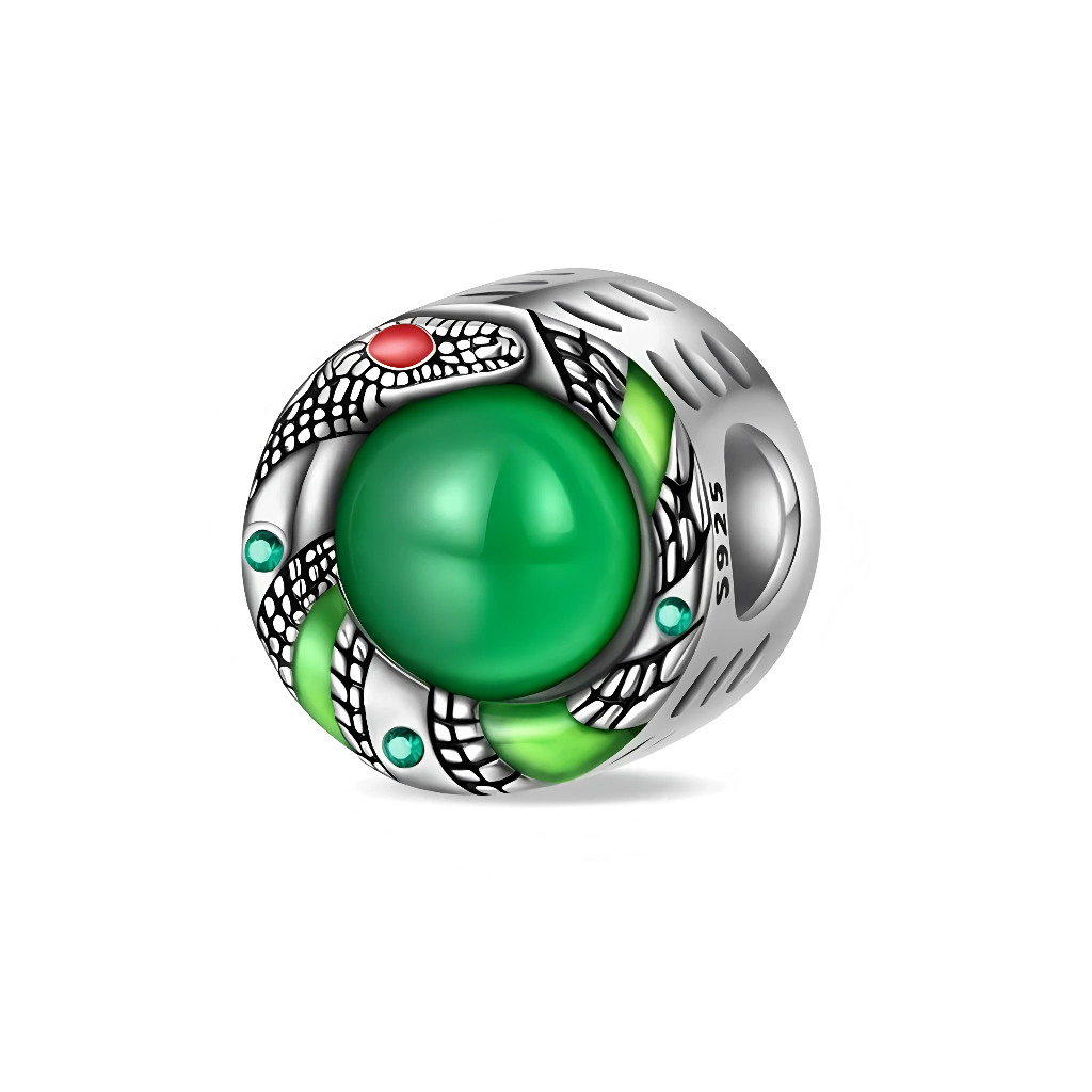 Ce charm en argent représente un serpent stylisé qui s’enroule autour d’un cabochon vert profond, évoquant une pierre d’émeraude lisse au centre du bijou. Les écailles noires et argent du serpent, rehaussées de petits accents verts et d’un détail rouge près de la tête, lui donnent une allure puissante et mystérieuse.