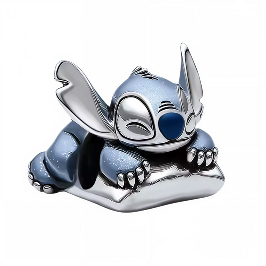 Ajoutez une touche de douceur et de fantaisie à votre collection avec ce charm irrésistible de Stitch endormi sur un oreiller. Cette scène attendrissante capture toute la tendresse du célèbre extraterrestre de Lilo &amp; Stitch, paisiblement installé pour une sieste bien méritée.

Fabriqué en argent 925, ce charm se distingue par ses finitions brillantes et ses détails minutieusement travaillés : les nuances bleues emblématiques de Stitch, ses grandes oreilles et ses petites griffes reposant délicatement su