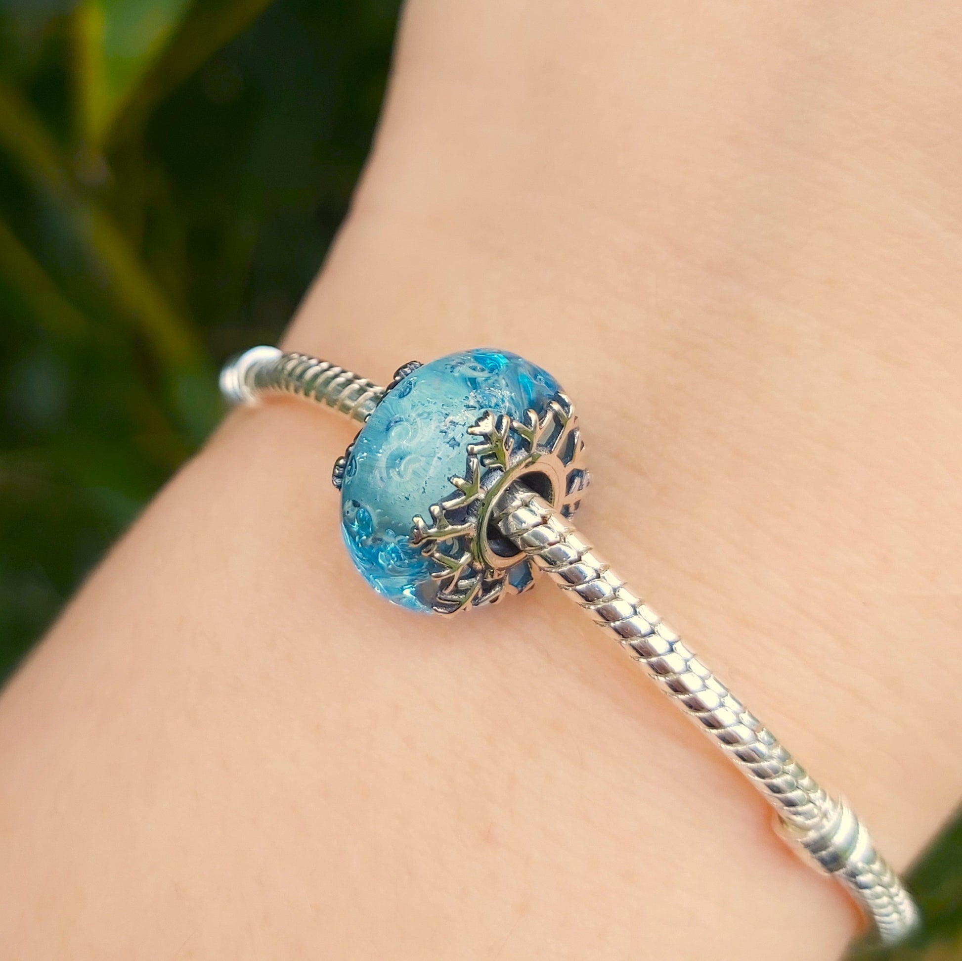 Apportez une touche hivernale à votre collection avec ce charm en verre de Murano Flocon de Neige. Ce bijou raffiné en verre de Murano présente des nuances cristallines et glacées, capturant la magie de l’hiver et l’élégance des flocons de neige. Avec des détails délicats en argent S925 et une compatibilité parfaite avec les bracelets Pandora, ce charm est idéal pour ajouter un éclat saisonnier tout en restant chic et intemporel. Idéal pour les amoureux de l'hiver et ceux qui apprécient la beauté naturelle 