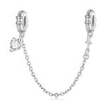 Cette chaîne de sécurité en argent 925 joue la carte de l’élégance classique, avec deux bélières finement ornées de motifs floraux et perlés façon pavé, qui encadrent délicatement le bracelet. Sur l’un des côtés, un pendentif cœur clair facetté, monté comme un solitaire, capte la lumière et apporte une touche bijou très raffinée.