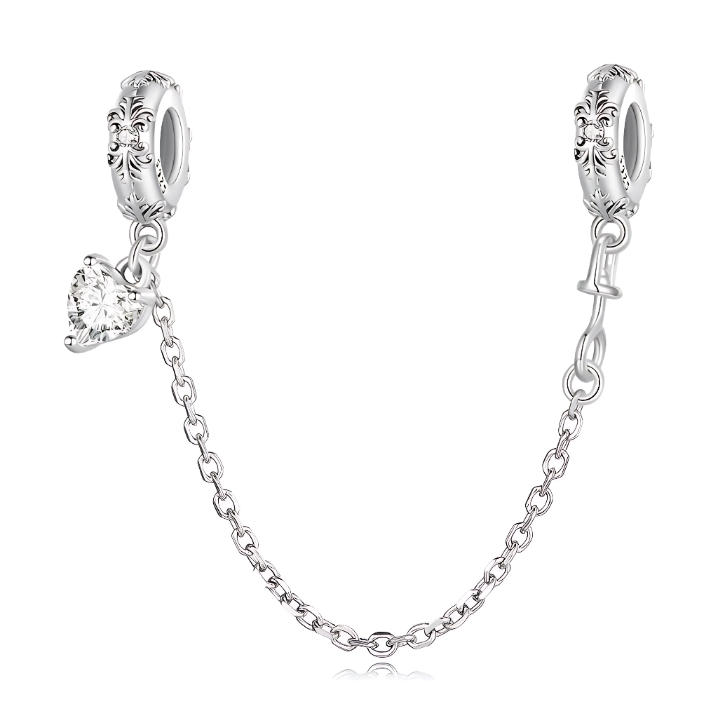 Cette chaîne de sécurité en argent 925 joue la carte de l’élégance classique, avec deux bélières finement ornées de motifs floraux et perlés façon pavé, qui encadrent délicatement le bracelet. Sur l’un des côtés, un pendentif cœur clair facetté, monté comme un solitaire, capte la lumière et apporte une touche bijou très raffinée.