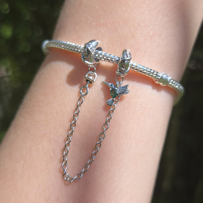 Apportez une touche de nature et de liberté à votre bracelet avec cette magnifique chaîne de sécurité ornée d’un oiseau aux détails verts. Fabriquée en argent 925, cette chaîne est sublimée par un adorable oiseau sculpté avec précision, accompagné de délicats accents verts qui rappellent les feuilles et la nature luxuriante.

En plus d’ajouter une touche poétique à votre bijou, cette chaîne de sécurité protège votre bracelet en empêchant les ouvertures accidentelles, garantissant ainsi la sécurité de vos ch