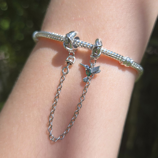 Apportez une touche de nature et de liberté à votre bracelet avec cette magnifique chaîne de sécurité ornée d’un oiseau aux détails verts. Fabriquée en argent 925, cette chaîne est sublimée par un adorable oiseau sculpté avec précision, accompagné de délicats accents verts qui rappellent les feuilles et la nature luxuriante.

En plus d’ajouter une touche poétique à votre bijou, cette chaîne de sécurité protège votre bracelet en empêchant les ouvertures accidentelles, garantissant ainsi la sécurité de vos ch