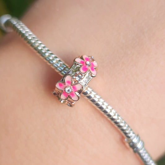 Apportez une touche florale et élégante à votre bracelet avec le Charm Clips - Espaceur Marguerite Rose en argent sterling S925. Ce charm raffiné est orné de petites marguerites roses délicates, symbolisant la beauté et la joie. Parfait pour les amateurs de fleurs et de designs subtils, cet espaceur permet de maintenir vos charms en place tout en ajoutant une note printanière et colorée à votre collection.