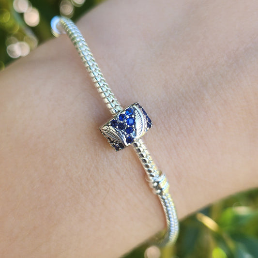 Évoquez légèreté et grâce avec le Charm Clips - Plume Courbe et Pavé. Conçu en argent sterling S925, ce charm représente une plume délicatement incurvée, ornée de petits pavés scintillants, symbolisant l'élégance et la liberté. Le design finement travaillé et ses pierres brillantes ajoutent une touche subtile de raffinement à votre bracelet tout en maintenant vos autres charms parfaitement en place.