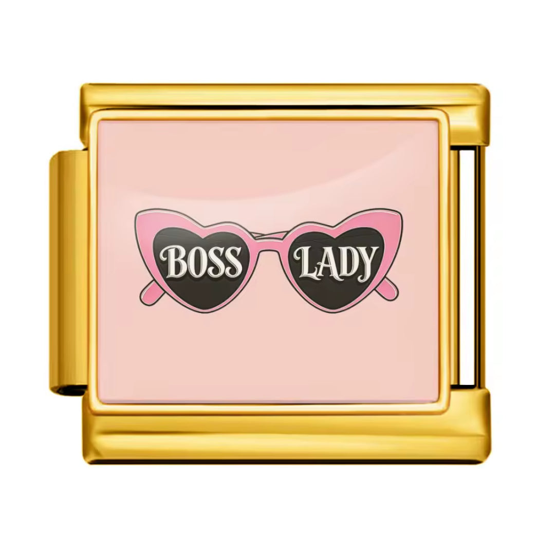Affirmez votre style avec ce charm au look audacieux et glamour. Sa couleur dorée lui donne une allure chic et lumineuse, tout en conservant l’esprit moderne, féminin et tendance de la&nbsp;Boss Lady. C’est un bijou parfait pour ajouter une touche élégante et fun à votre collection.

Caractéristiques :

- Couleur : Doré.
- Thème : Mode, glamour, boss lady.
- Design : Lunettes roses, silhouette élégante, finitions dorées.
- Compatibilité : Bracelet charms ou collection pop fashion.