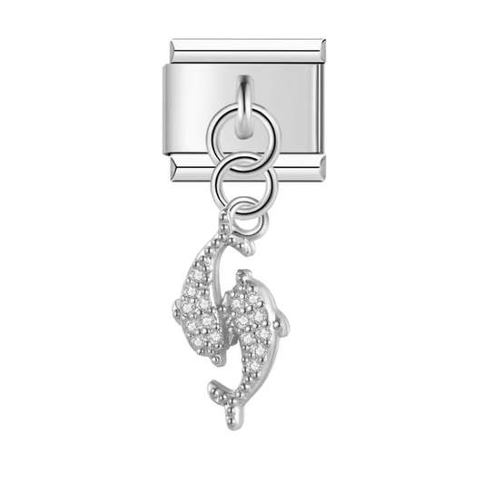 Ce charm italien pendentif en acier inoxydable argenté représente deux dauphins élégamment croisés, symbolisant l’harmonie et la complicité. Avec ses lignes fluides et son design soigné, il apporte une touche marine et raffinée à votre bracelet. Facile à fixer, il s’adapte parfaitement à nos bracelets composés de 17 maillons extensibles et réglables, convenant à toutes les tailles de poignet. Compatible avec tous nos charms italiens, ce bijou est idéal pour personnaliser votre bracelet avec une note d’éléga