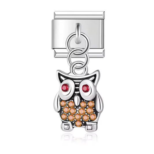 Ce charm italien pendentif en acier inoxydable argenté représente un hibou délicat, orné d’une pierre brillante orange sur le ventre qui apporte une touche chaleureuse et lumineuse. Symbole de sagesse et de mystère, ce bijou élégant ajoute une note raffinée et originale à votre bracelet. Le format pendentif apporte du mouvement et met en valeur l’éclat de la pierre à chaque geste. Facile à accrocher, il s’adapte à nos bracelets composés de 17 maillons extensibles et réglables, convenant à toutes les tailles