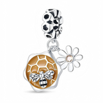 Ce charm pendentif en argent célèbre la nature avec un médaillon en forme de rayon de miel doré en relief, sur lequel une petite abeille brillante semble se poser. À ses côtés, une délicate marguerite argentée au centre serti d’un cristal champagne ajoute une touche fleurie, tandis que la bélière est décorée de motifs alvéolés rappelant une ruche.