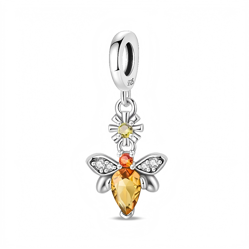 Ce charm pendentif en argent représente une abeille lumineuse dont le corps est un cristal facetté couleur miel en forme de goutte, surmonté d’une petite tête orange. Ses ailes sont serties de zircons clairs pour un éclat intense, et un petit motif de fleur solaire avec cristal jaune relie l’abeille à la bélière lisse.