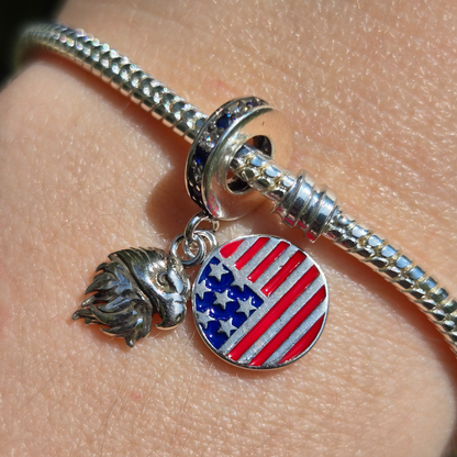 Affichez fièrement les symboles de la liberté et du patriotisme avec le Charm - Aigle et Drapeau des États-Unis, en argent sterling S925. Ce charm combine la majesté de l'aigle, emblème national américain, et les étoiles et rayures du célèbre drapeau des États-Unis. Idéal pour les voyageurs, les amoureux de la culture américaine ou ceux qui souhaitent porter un symbole de fierté et de force.
