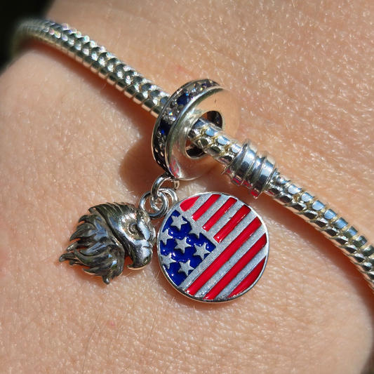 Affichez fièrement les symboles de la liberté et du patriotisme avec le Charm - Aigle et Drapeau des États-Unis, en argent sterling S925. Ce charm combine la majesté de l'aigle, emblème national américain, et les étoiles et rayures du célèbre drapeau des États-Unis. Idéal pour les voyageurs, les amoureux de la culture américaine ou ceux qui souhaitent porter un symbole de fierté et de force.