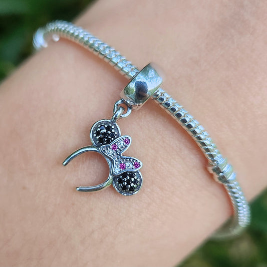 Ajoutez une touche de charme et d'élégance Disney à votre collection avec ce charm pendentif représentant le célèbre bandeau de Minnie Mouse. Fabriqué en argent sterling 925, ce pendentif capture la délicatesse du bandeau à pois emblématique de Minnie avec des détails raffinés et une finition brillante. Parfait pour les fans de Minnie et les amateurs de bijoux Disney, ce charm est une manière élégante de célébrer l'esprit joyeux de l'univers Disney sur votre bracelet ou collier.