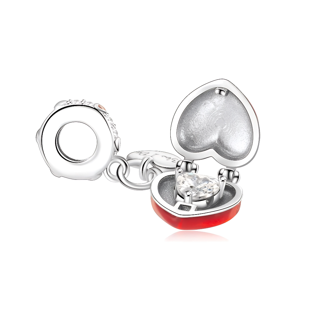 Ce charm pendentif en argent est une véritable déclaration d’amour, avec un grand cœur rouge brillant portant l’inscription “Marry Me” et un cœur plus petit en argent gravé “Yes I Do”. Le grand cœur s’ouvre comme un écrin pour révéler à l’intérieur une pierre claire en forme de cœur, rappelant une bague de fiançailles cachée, tandis que la bélière pavée de zircons et ornée d’un petit cœur rouge ajoute une touche d’éclat romantique.