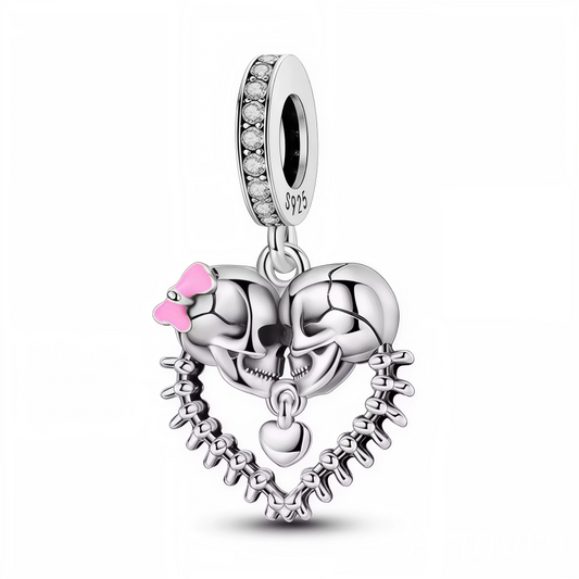 Affichez un amour sans limite et un style décalé avec ce charm unique en argent 925 ! Cette création audacieuse met en scène deux crânes formant un cœur, reliés par une chaîne d’os pour une touche résolument originale et rock’n’roll. Un joli nœud rose délicat apporte une note de tendresse à l’ensemble. Le tout est sublimé par une attache ornée de pierres scintillantes, parfaite pour illuminer vos bracelets à charms d’un éclat rebelle et romantique.