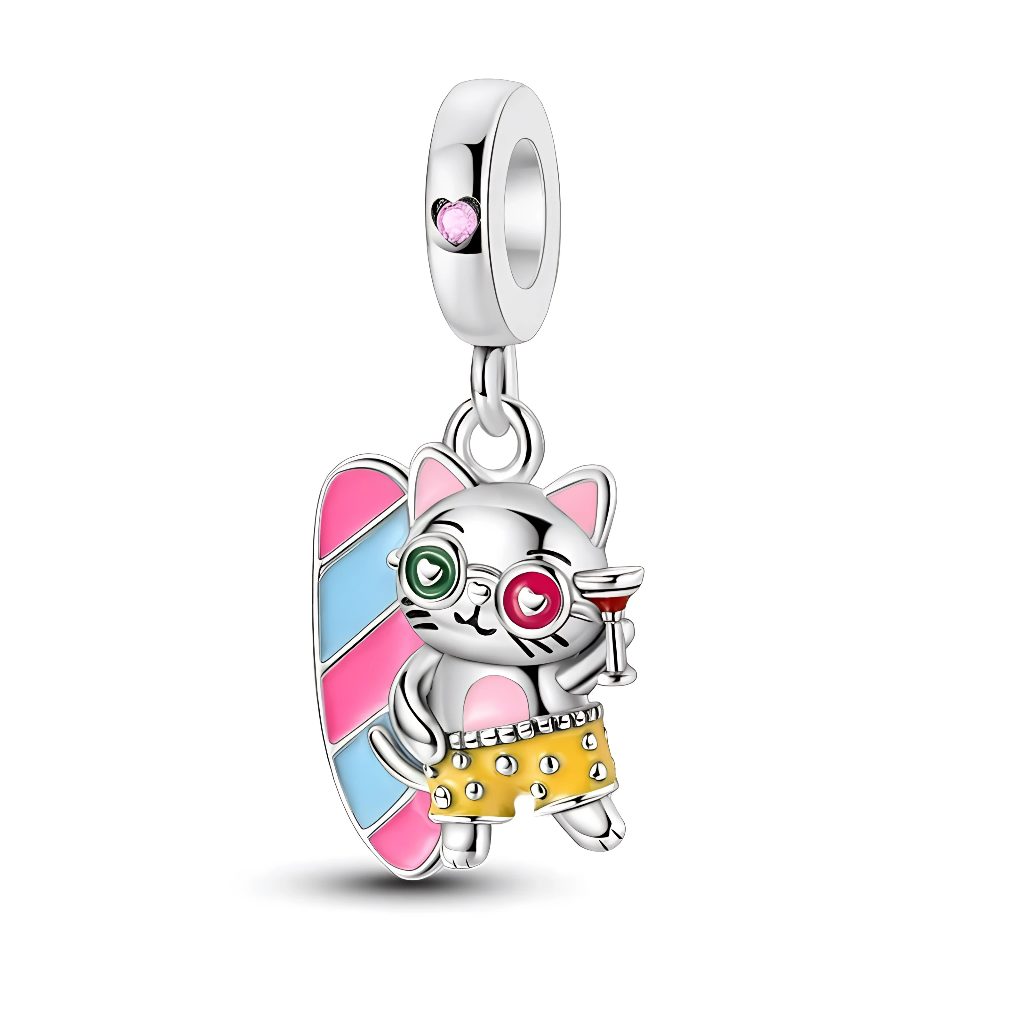 Ce charm pendentif en argent représente un adorable chat surfeur prêt pour des vacances au soleil, tenant un cocktail à la patte et portant un short de bain jaune décoré de petits détails. Derrière lui, une grande planche de surf aux bandes rose et bleu pastel apporte une touche colorée, tandis que la bélière est ornée d’un petit cristal rose qui rappelle l’esprit joyeux et détendu de l’été.