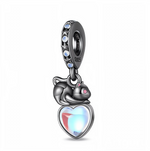 Ce charm pendentif en argent 925 noirci met en scène un petit chat lové au‑dessus d’un grand cœur bombé effet opale, dont les reflets bleus et rosés rappellent la lueur de la lune. La bélière sombre est décorée d’étoiles en relief serties de petites pierres bleues, renforçant l’ambiance nocturne et mystérieuse du bijou.