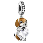Ce charm pendant en argent 925 représente un petit chien aux oreilles tombantes, au pelage brun et blanc, assis sagement. Entre ses pattes, il serre un grand cœur en cristal transparent facetté, tandis que la bélière est décorée d’une frise de petits cœurs pour souligner le thème de l’amour.

Caractéristiques :

- Matière : Argent 925 avec émail brun et blanc, pierre synthétique transparente.
- Design : Chien assis tenant un cœur facetté, bélière ornée de cœurs gravés.
- Coloris : Argent lumineux, brun chau