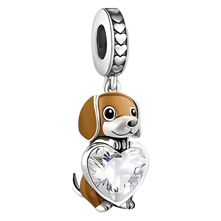 Ce charm pendant en argent 925 représente un petit chien aux oreilles tombantes, au pelage brun et blanc, assis sagement. Entre ses pattes, il serre un grand cœur en cristal transparent facetté, tandis que la bélière est décorée d’une frise de petits cœurs pour souligner le thème de l’amour.

Caractéristiques :

- Matière : Argent 925 avec émail brun et blanc, pierre synthétique transparente.
- Design : Chien assis tenant un cœur facetté, bélière ornée de cœurs gravés.
- Coloris : Argent lumineux, brun chau