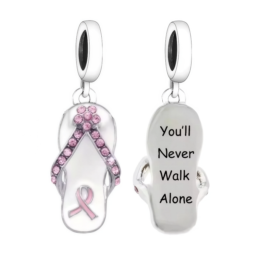 Ce pendentif en forme de claquette met en lumière le ruban rose, symbole international de la lutte contre le cancer du sein, souligné par des strass roses pour une touche lumineuse et engagée. Le revers gravé “You’ll Never Walk Alone” rappelle un message de soutien et de solidarité porté par de nombreux charms de sensibilisation, souvent compatibles avec les bracelets de style européen type Pandora. L’ensemble associe métal argenté et détails émaillés/zircons roses pour un bijou à la fois doux et fort, pens