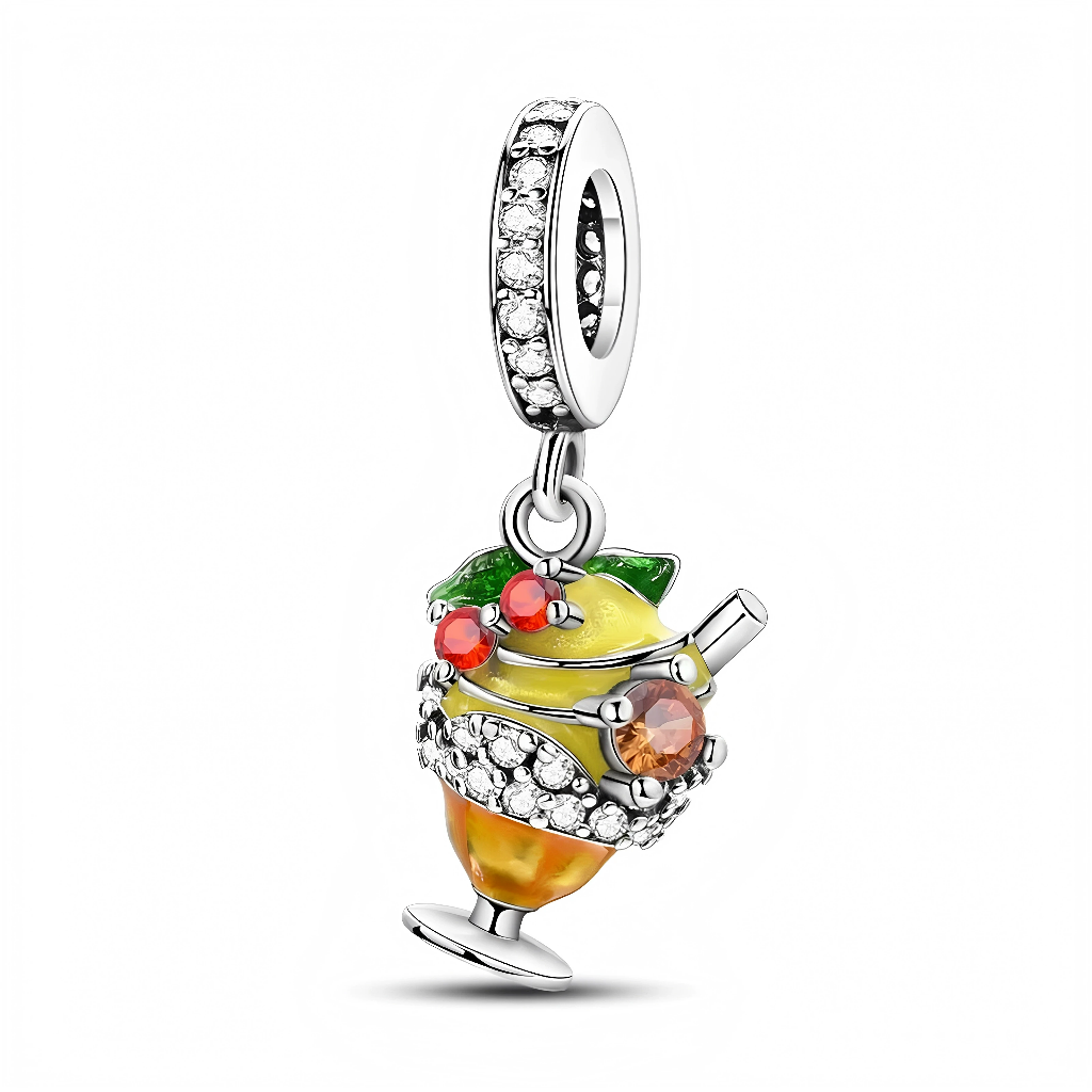 Ce charm pendentif en argent représente un délicieux cocktail citronné servi dans un verre à pied, avec un citron jaune brillant, des feuilles vertes et de petites billes rouges façon fruits, le tout rehaussé d’un pavage de cristaux étincelants. La bélière sertie de pierres claires prolonge cet effet lumineux, parfait pour évoquer les vacances, les soirées d’été ou un amour assumé pour les drinks colorés.